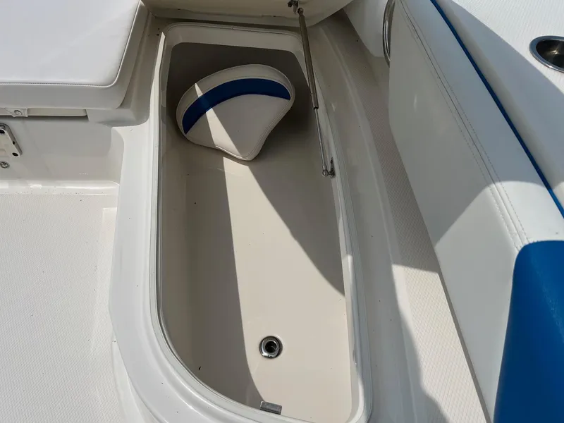 Slide: The Image of 2018 Robalo 246 Cayman boat storage compartment with cushion, white and blue interior. - 30