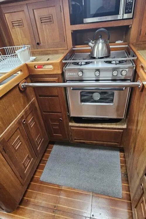 Slide: The Image of 1983 Cheoy Lee Pedrick 41 yacht kitchen with wooden cabinets and stainless steel stove. - 33