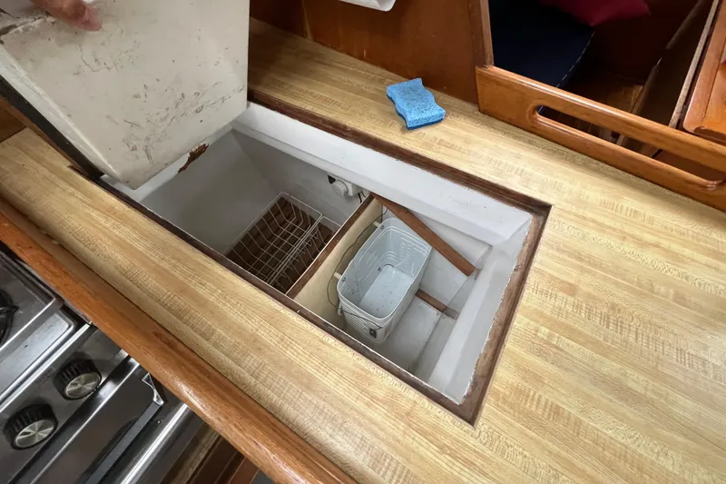 Slide: The Image of 1983 Cheoy Lee Pedrick 41 yacht interior with open storage compartment in wooden countertop. - 34