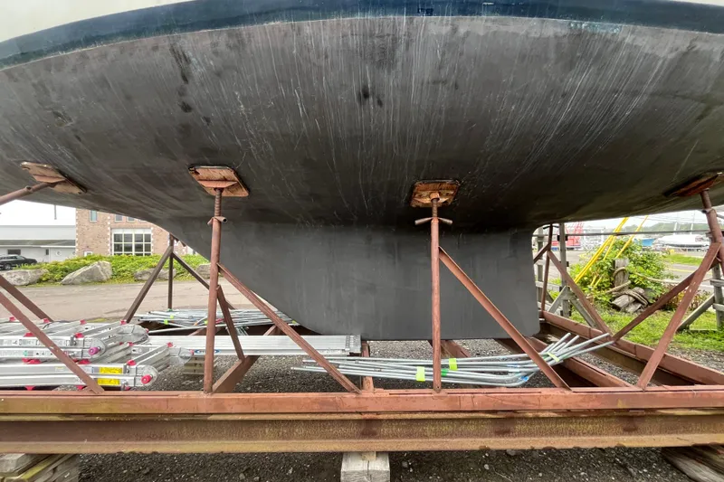 Slide: The Image of 1983 Cheoy Lee Pedrick 41 sailboat hull on a metal stand, outdoor setting. - 4