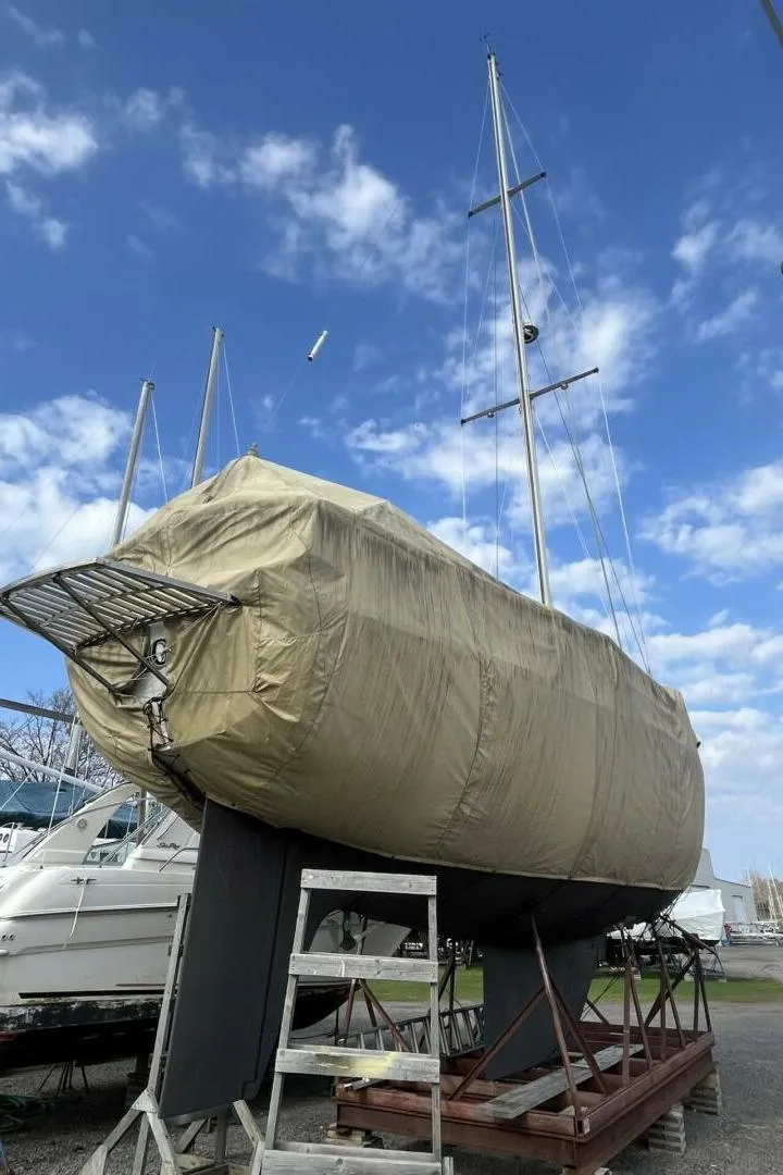 Slide: The Image of 1983 Cheoy Lee Pedrick 41 sailboat covered, docked under a blue sky with clouds. - 51
