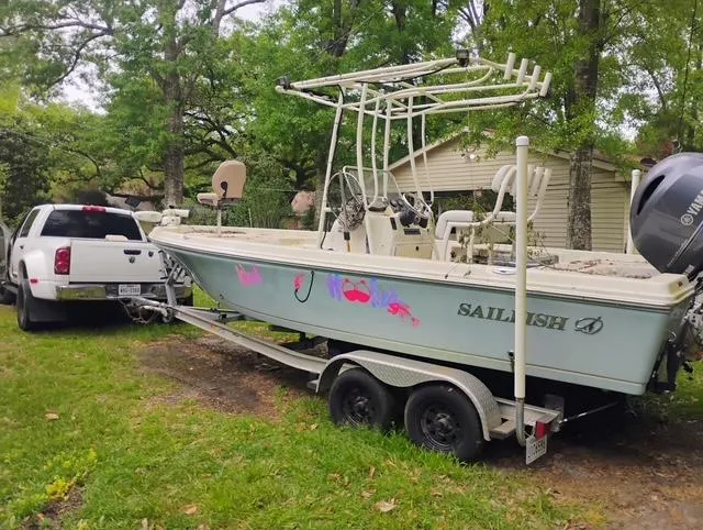 Slide: The Image of 2017 Sailfish 2100 BB Bay Boat on trailer, parked beside a white truck in a grassy area. - 6