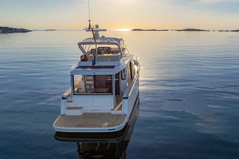 Slide: The Image of 2025 Nimbus 495 Flybridge yacht on serene water at sunset. - 2
