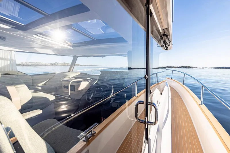 Slide: The Image of 2025 Nimbus 495 Flybridge yacht with sleek design and spacious interior on calm waters. - 14