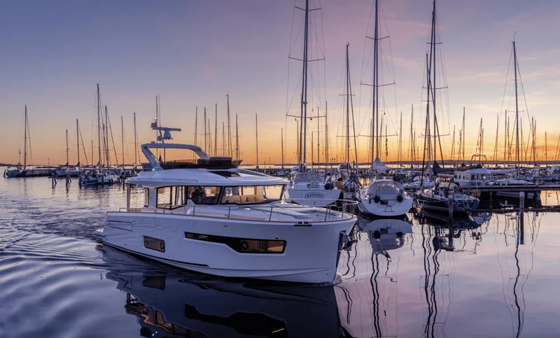 Slide: The Image of 2025 Nimbus 495 Flybridge yacht in a serene marina at sunset. - 26