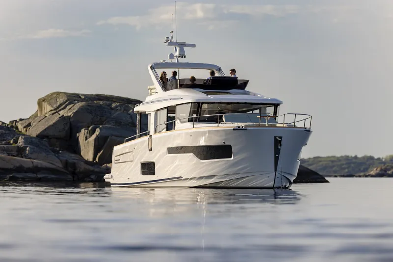 Slide: The Image of 2025 Nimbus 495 Flybridge yacht cruising near rocky shoreline. - 29