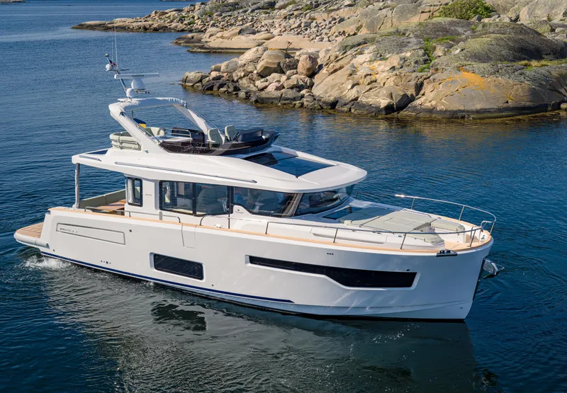 Slide: The Image of 2025 Nimbus 495 Flybridge yacht cruising near rocky shoreline. - 35