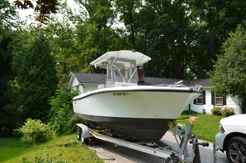 Slide: The Image of 2007 Edgewater 228CC boat on trailer in residential driveway, surrounded by greenery. - 3