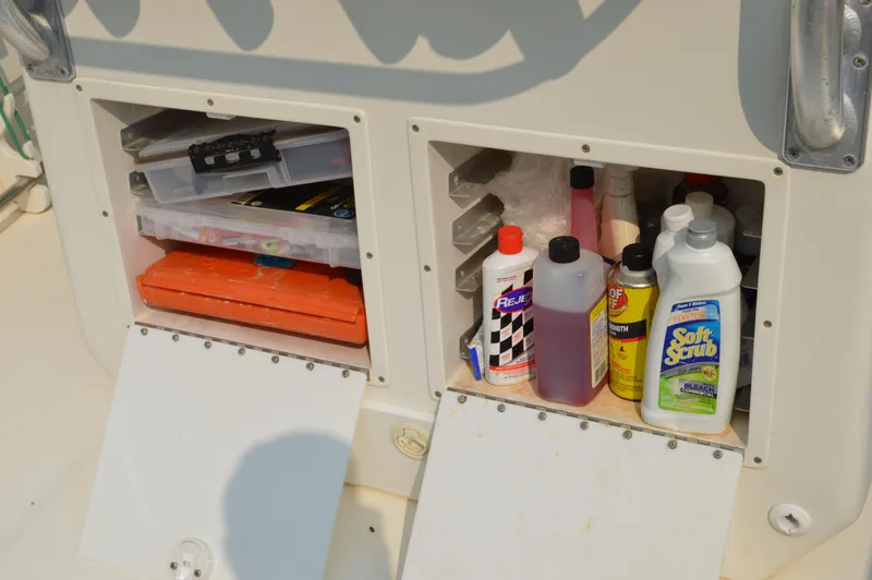 Slide: The Image of Storage compartments on a 2007 Edgewater 228CC boat with cleaning supplies and tackle boxes. - 38