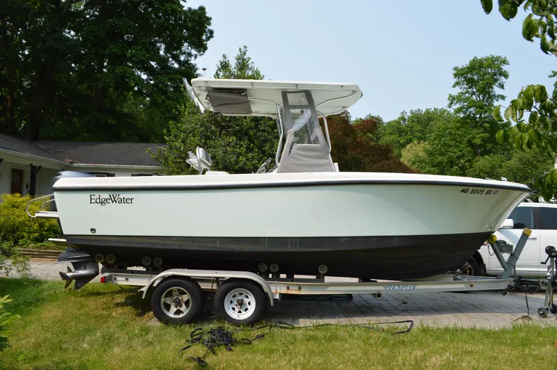 Slide: The Image of 2007 Edgewater 228CC boat on trailer, parked outdoors with lush greenery. - 6
