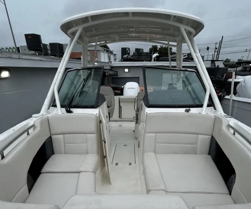 Slide: The Image of 2018 Boston Whaler 230 Vantage boat interior with seating and canopy, docked outdoors. - 4