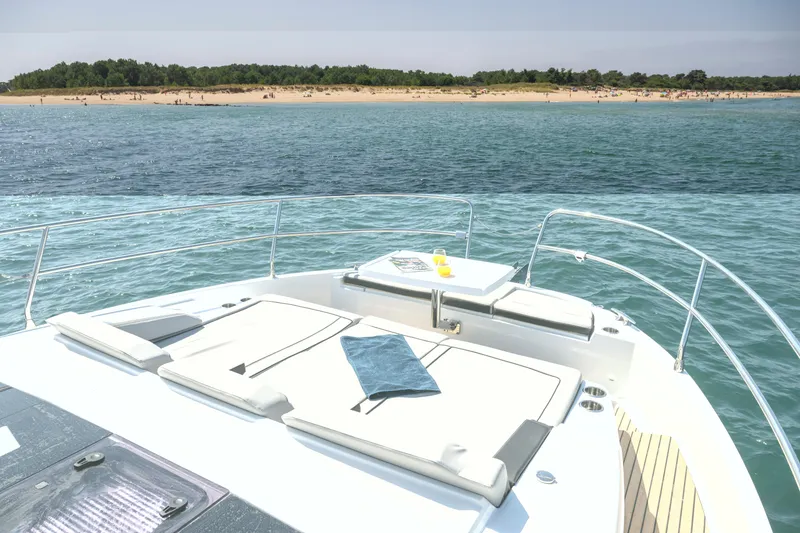 Slide: The Image of 2026 Jeanneau NC1295 Fly yacht with sunbathing deck, ocean view, and distant beach. - 7