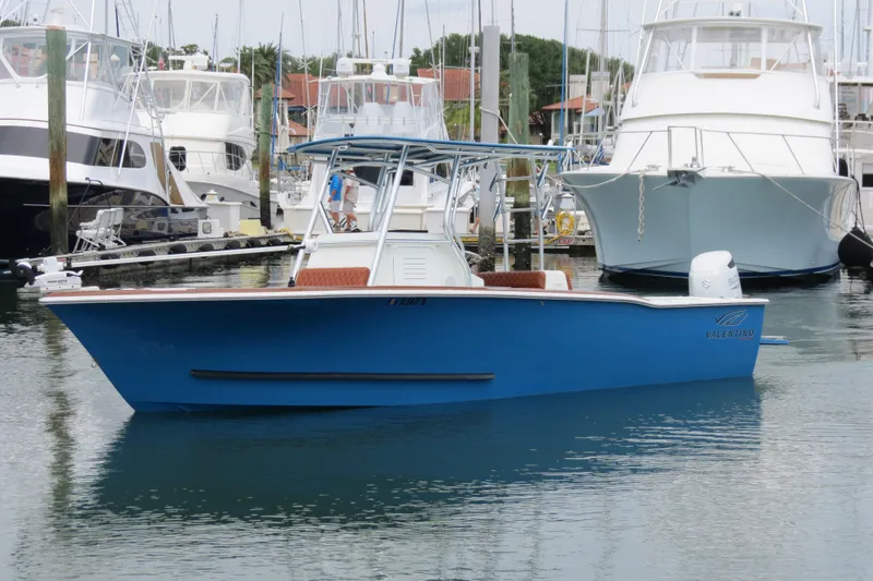 Slide: The Image of 2022 Valentino 28CC boat docked in marina, surrounded by other vessels. - 2