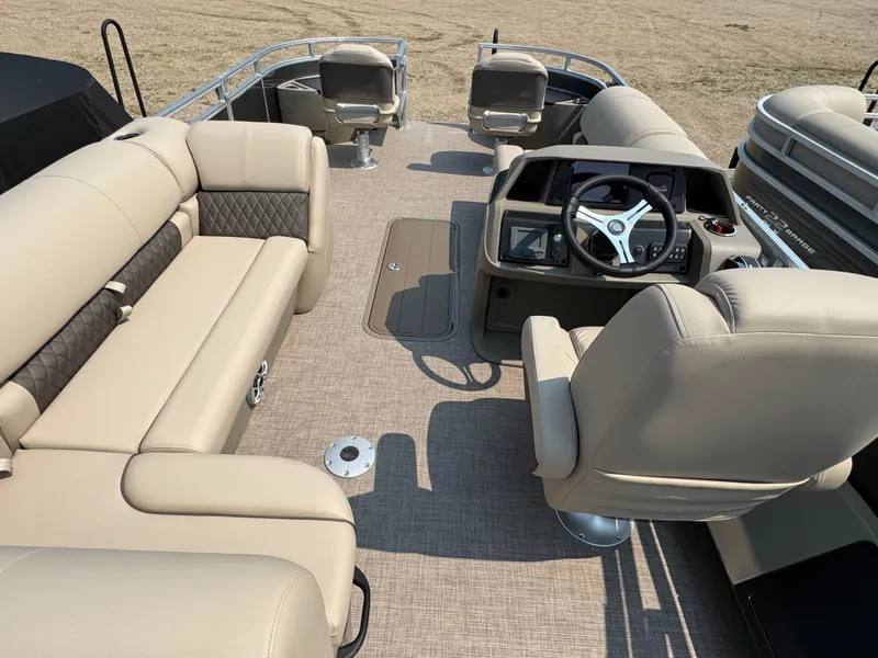 Slide: The Image of 2025 Sun Tracker Fishin' Barge 22 XP3 interior with beige seating and steering console. - 19