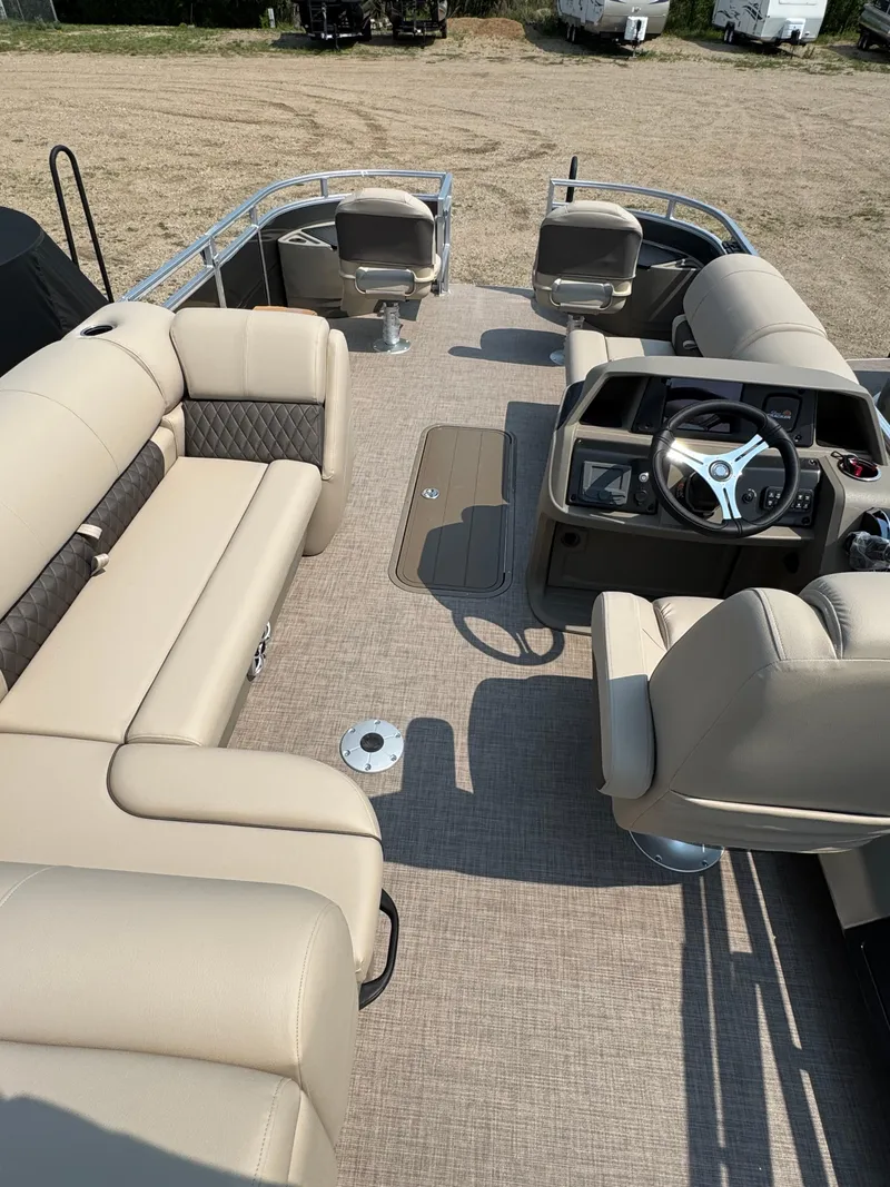 Slide: The Image of 2025 Sun Tracker Fishin' Barge 22 XP3 interior with beige seating and steering console. - 20