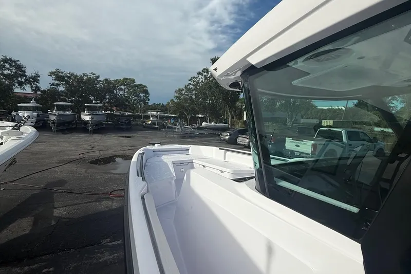 Slide: The Image of 2025 Axopar 29 CCX boat in a marina, surrounded by parked vehicles and trees. - 4