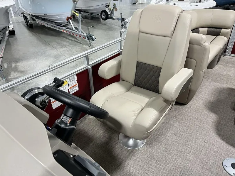 Slide: The Image of 2025 Sun Tracker PARTY BARGE® 22 RF DLX boat interior with beige captain's chair and steering wheel. - 12