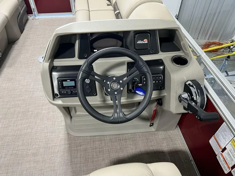 Slide: The Image of 2025 Sun Tracker PARTY BARGE® 22 RF DLX steering console with controls and beige seating. - 13