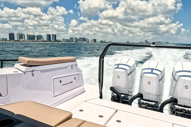 Slide: The Image of 2026 Axopar 45 Cross Top boat cruising with city skyline in background. - 13