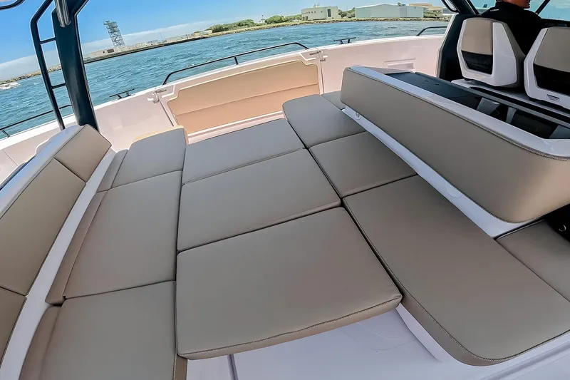 Slide: The Image of 2026 Axopar 45 Cross Top boat interior with beige seating, docked by the water. - 27