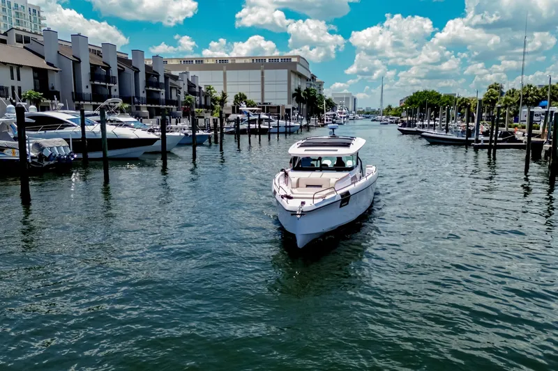 Slide: The Image of 2026 Axopar 45 Cross Top boat cruising in a marina under a bright blue sky. - 4