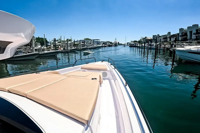 Slide: The Image of 2026 Axopar 45 Cross Top boat cruising in a sunny marina with clear blue skies. - 43