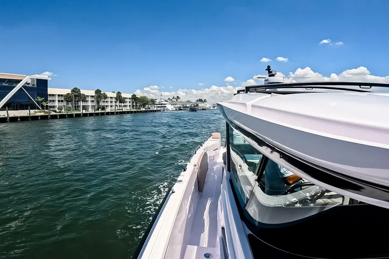Slide: The Image of 2026 Axopar 45 Cross Top cruising near waterfront buildings under clear blue sky. - 48