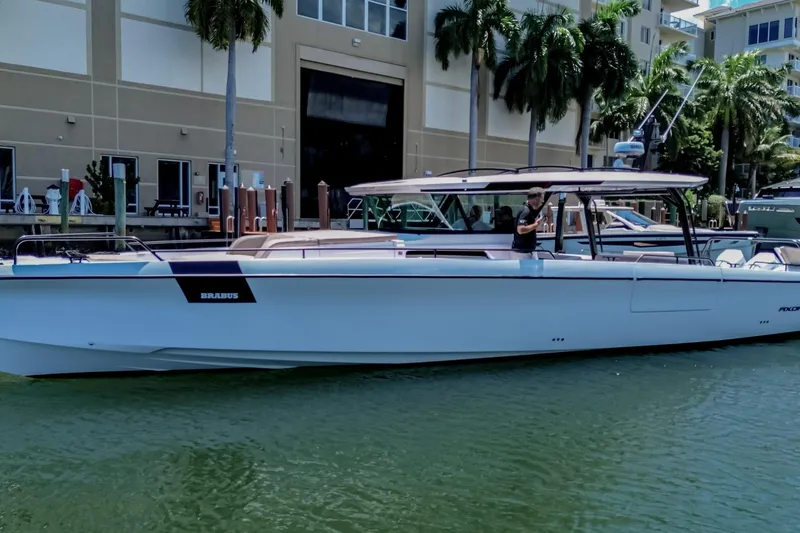 Slide: The Image of 2026 Axopar 45 Cross Top boat docked near palm trees and buildings. - 49