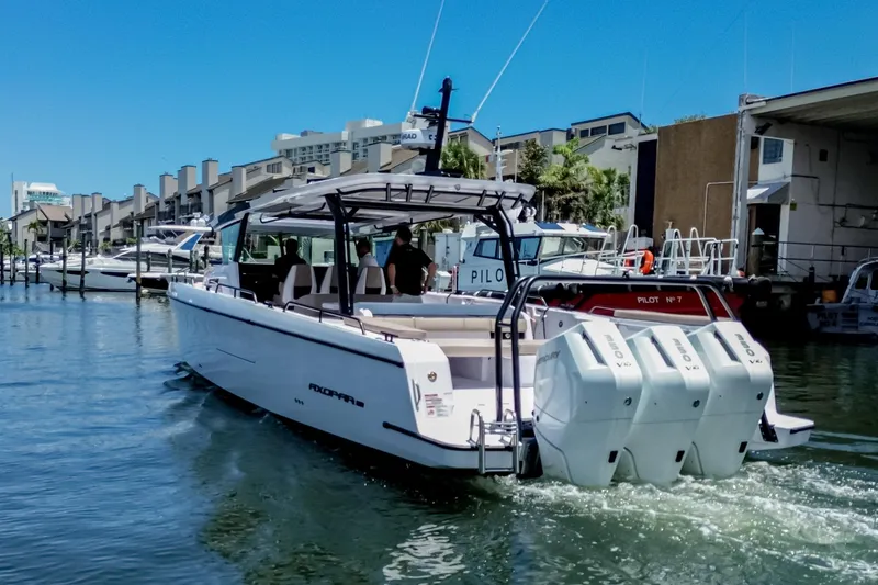 Slide: The Image of 2026 Axopar 45 Cross Top boat cruising in a marina with modern buildings. - 5