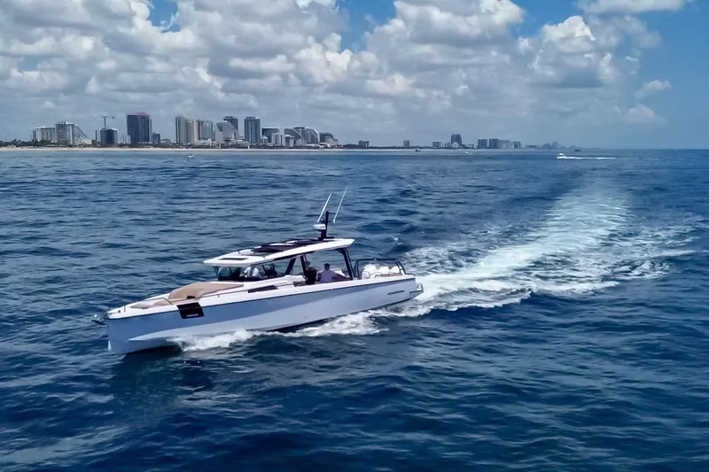 Slide: The Image of 2026 Axopar 45 Cross Top cruising on ocean with city skyline in background. - 52