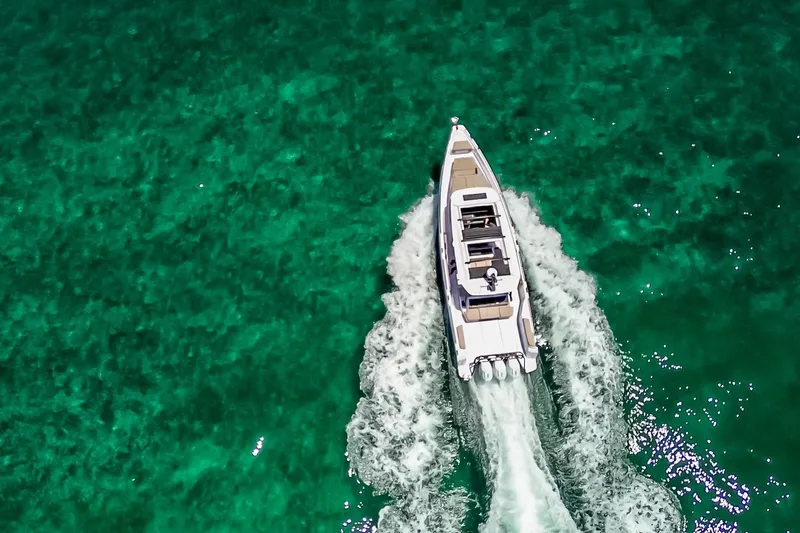 Slide: The Image of 2026 Axopar 45 Cross Top cruising on clear turquoise waters, aerial view. - 9