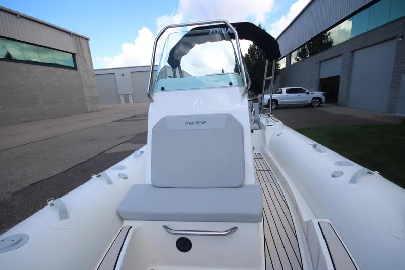 Slide: The Image of 2025 Zodiac Medline 5.8 NEO boat with 115hp engine, docked near industrial buildings. - 15