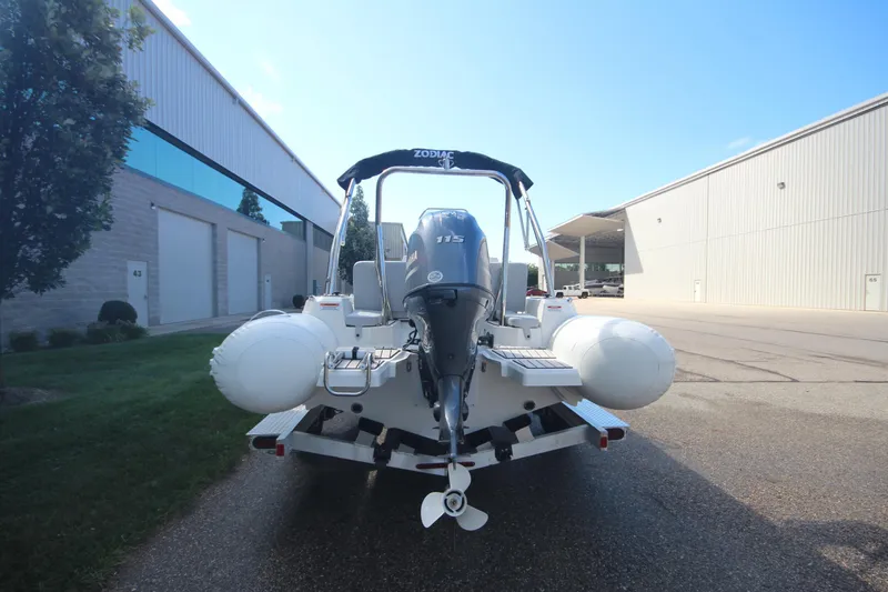 Slide: The Image of 2025 Zodiac Medline 5.8 NEO boat with 115hp engine, parked outside industrial building. - 4