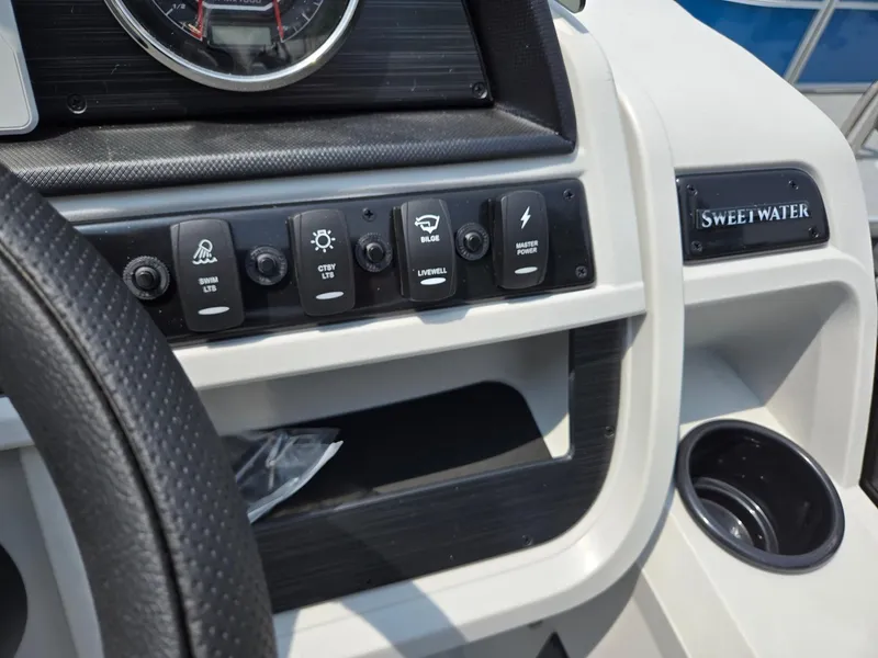 Slide: The Image of Control panel of 2026 Godfrey Sweetwater 2286 QS boat with various switches and cup holder. - 16
