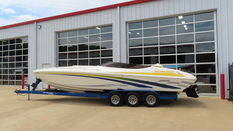 Slide: The Image of 2002 Nordic 28 Heat boat on trailer, parked outside a garage with large windows. - 2