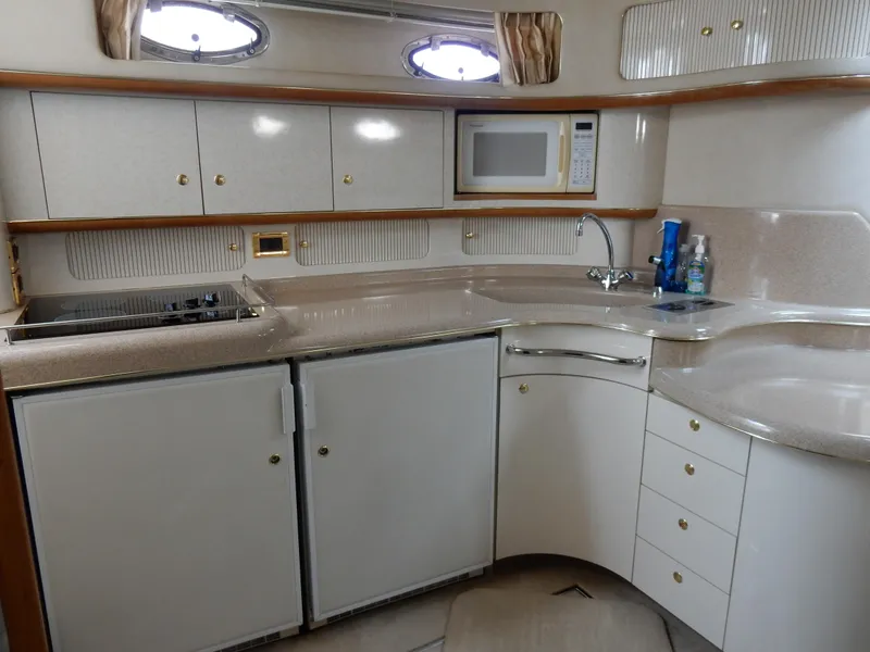 Slide: The Image of 1997 Sea Ray 450 yacht kitchen with white cabinets, microwave, and sink. - 17