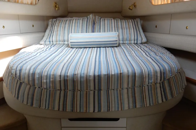 Slide: The Image of 1997 Sea Ray 450 yacht cabin with striped bedding and cozy interior. - 24