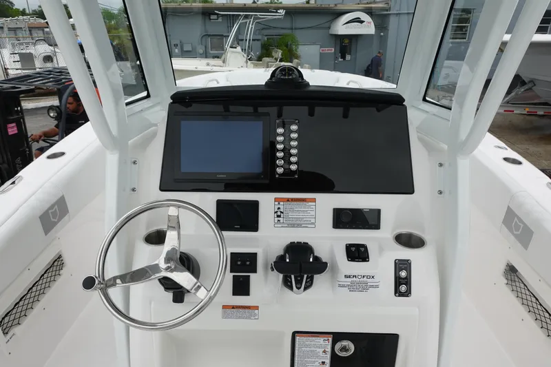 Slide: The Image of 2025 Sea Fox 268 Commander boat dashboard with steering wheel and navigation controls. - 2
