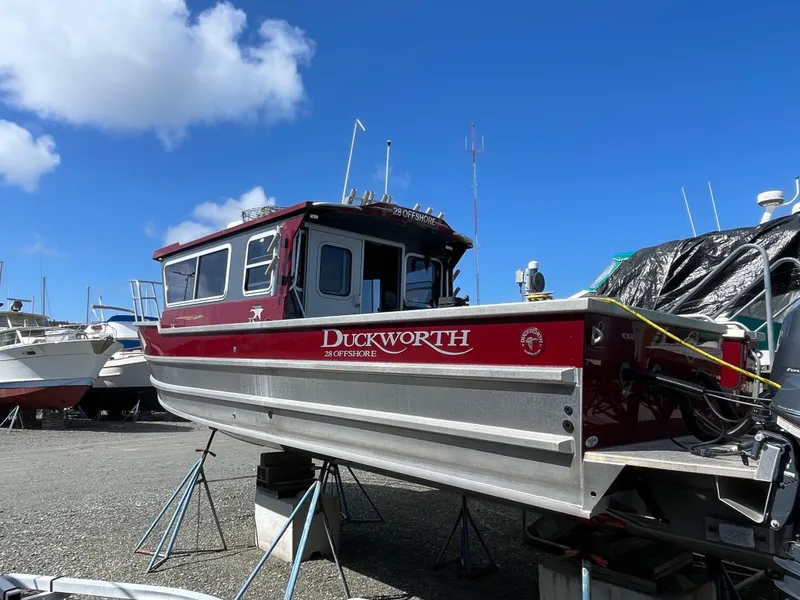 Slide: The Image of 2018 Duckworth 28 Offshore boat on stands, red and silver, under a clear blue sky. - 28