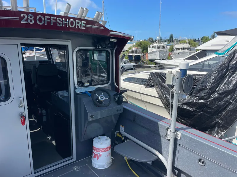 Slide: The Image of 2018 Duckworth 28 Offshore boat docked at marina, featuring steering wheel and cabin entrance. - 30