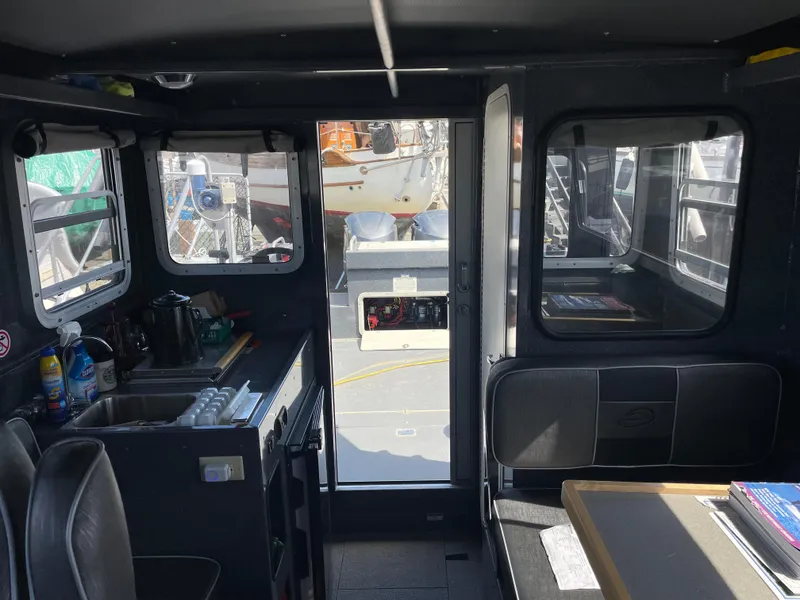 Slide: The Image of Interior of a 2018 Duckworth 28 Offshore boat, featuring a compact kitchen and seating area. - 42