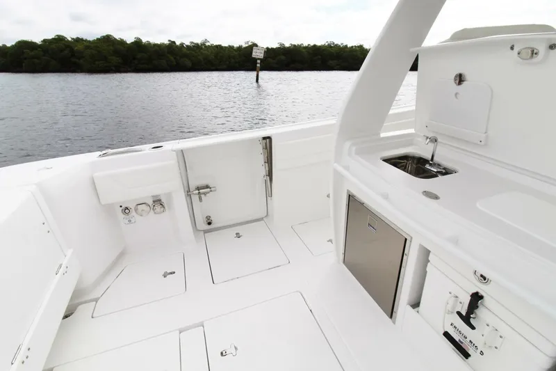 Slide: The Image of 2024 Intrepid 375 Nomad SE boat interior with sink and storage, near calm waters. - 11