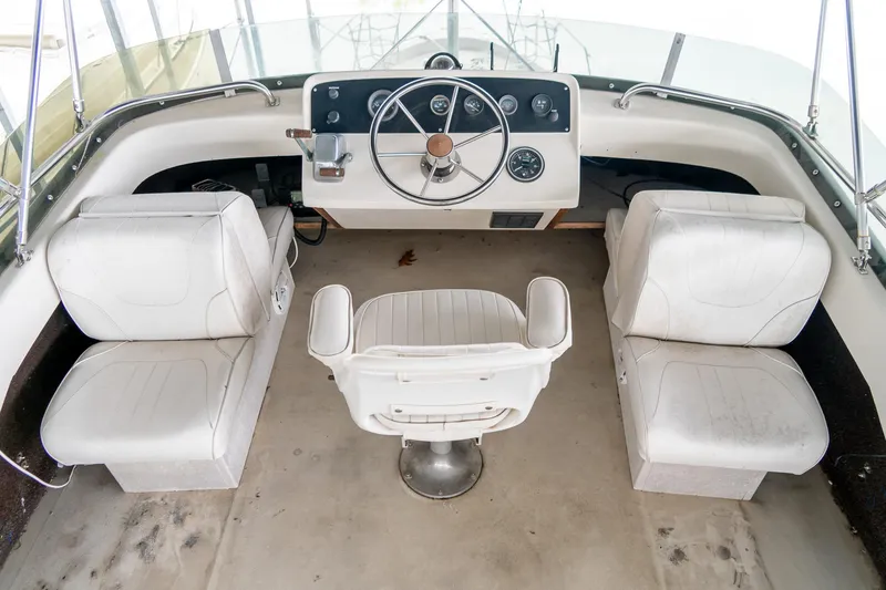 Slide: The Image of 1979 Mainship 34 boat interior with white seating and steering wheel. - 10