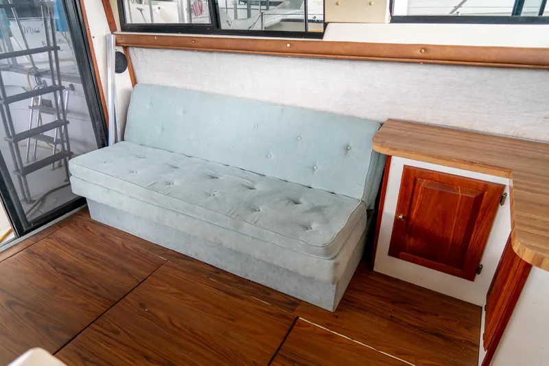 Slide: The Image of 1979 Mainship 34 interior with a light blue sofa, wooden flooring, and cabinetry. - 15