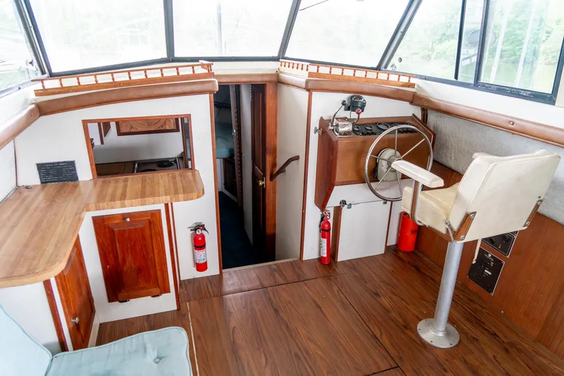 Slide: The Image of 1979 Mainship 34 boat interior with wooden flooring, steering wheel, and seating area. - 18