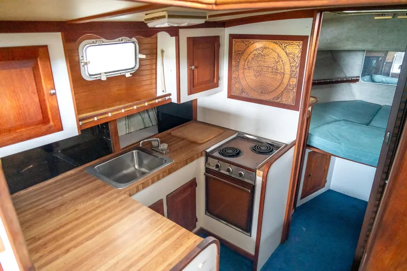Slide: The Image of 1979 Mainship 34 interior with wood cabinetry, compact kitchen, and cozy sleeping area. - 22
