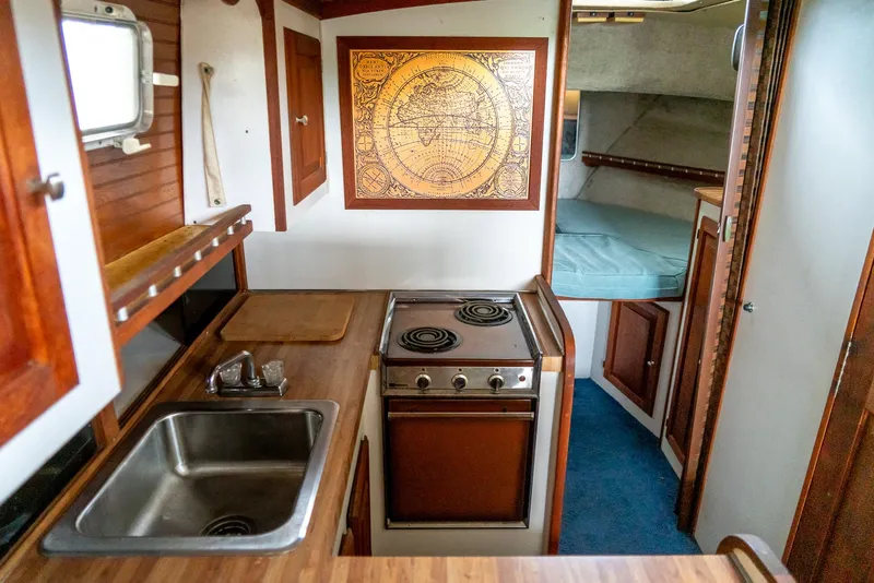 Slide: The Image of 1979 Mainship 34 boat interior with kitchen, stove, sink, and cozy sleeping area. - 23