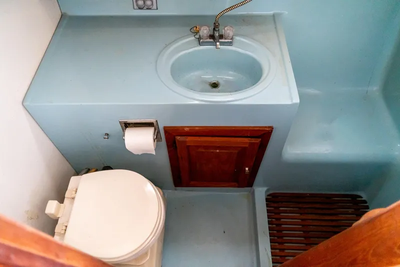 Slide: The Image of 1979 Mainship 34 boat bathroom with sink, toilet, and wooden cabinet. - 25