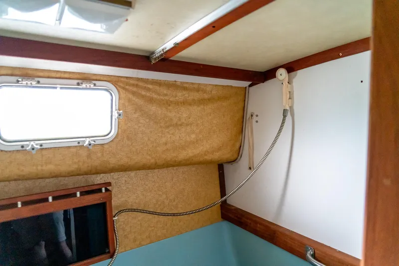 Slide: The Image of Interior of 1979 Mainship 34 boat, featuring a window, showerhead, and wood accents. - 26
