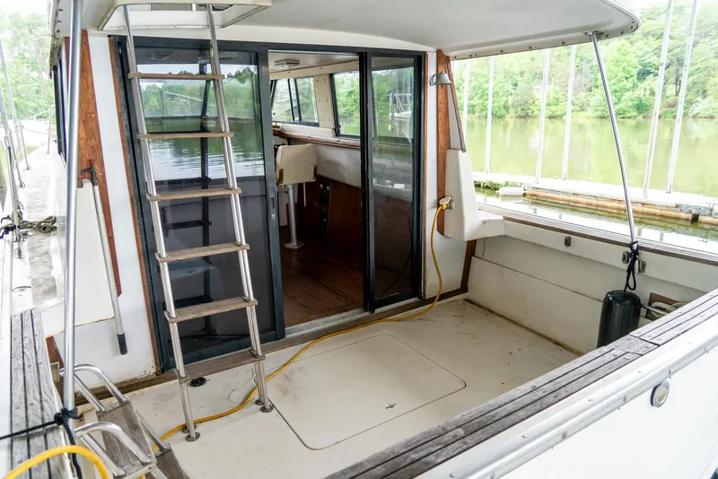 Slide: The Image of 1979 Mainship 34 boat with open deck, sliding glass doors, and ladder, docked by a serene lake. - 7